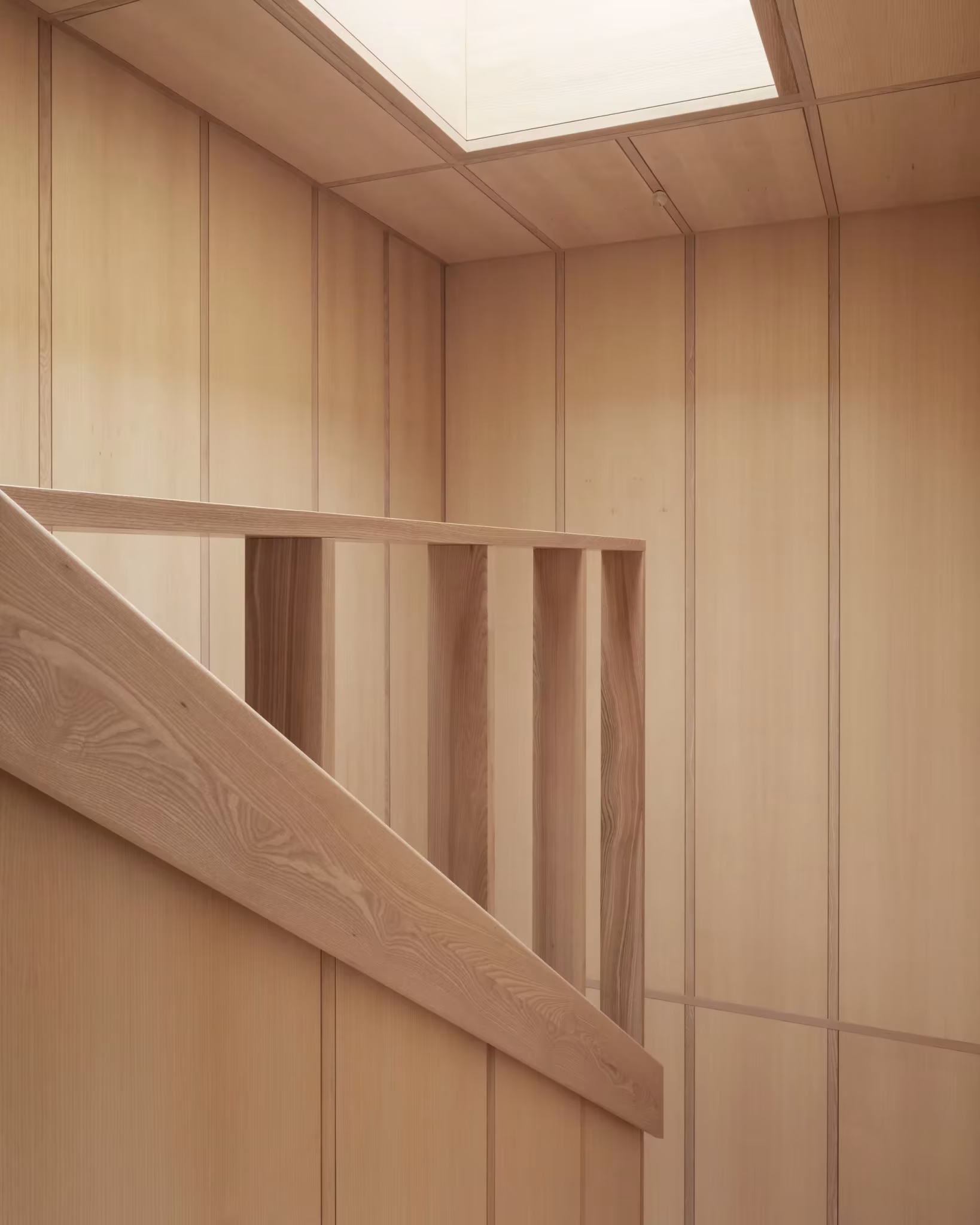 Caja de escalera de madera con balaustrada de listones y luz cenital en la casa de Fohlenweg