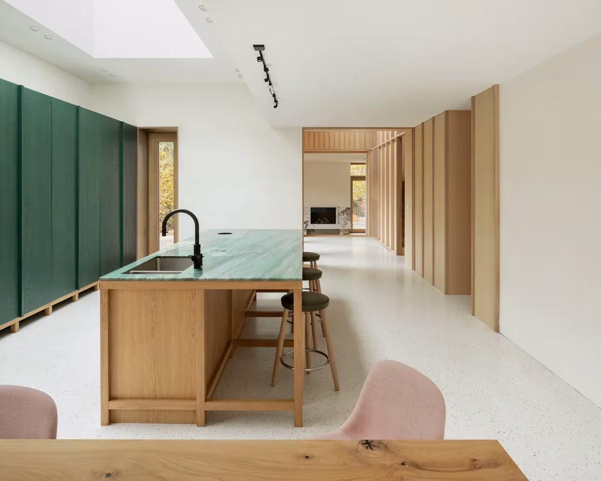 Cocina con isla de roble y encimera verde bajo un lucernario, abierta al pasillo de madera en Fohlenweg