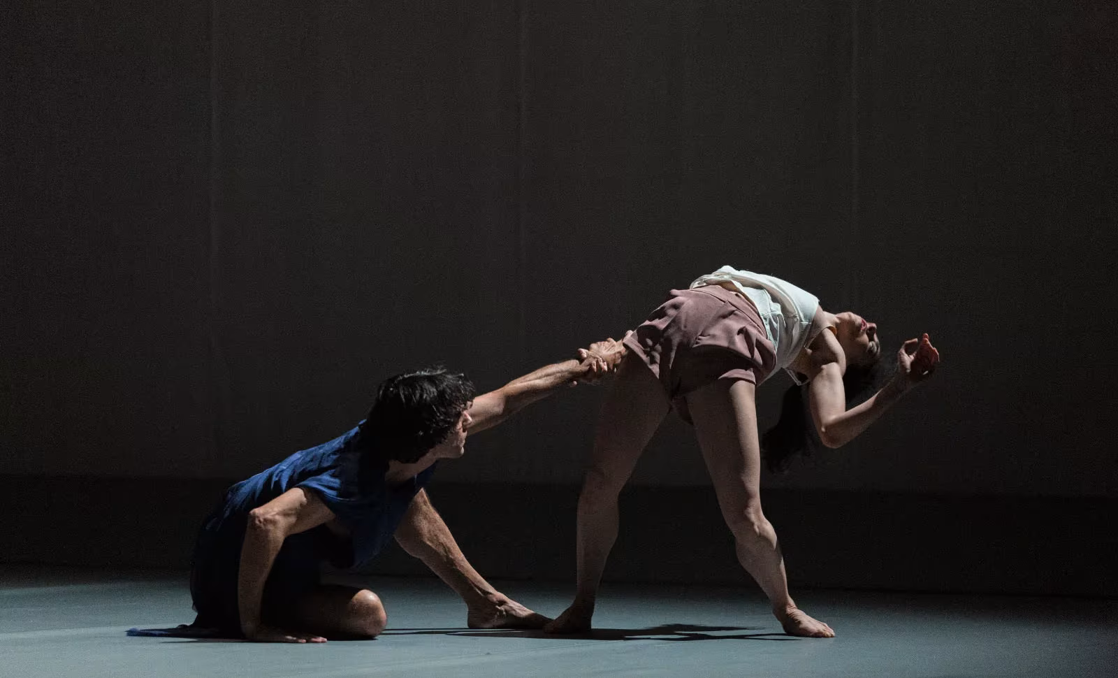 Dos bailarines en un dúo sobre el escenario en penumbra, en In Paradisum de Antonio Ruz