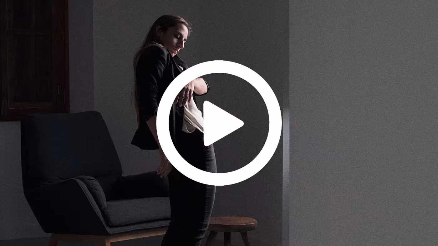 Fotograma de vídeo de Derek Pedros con una mujer en penumbra junto a un sillón