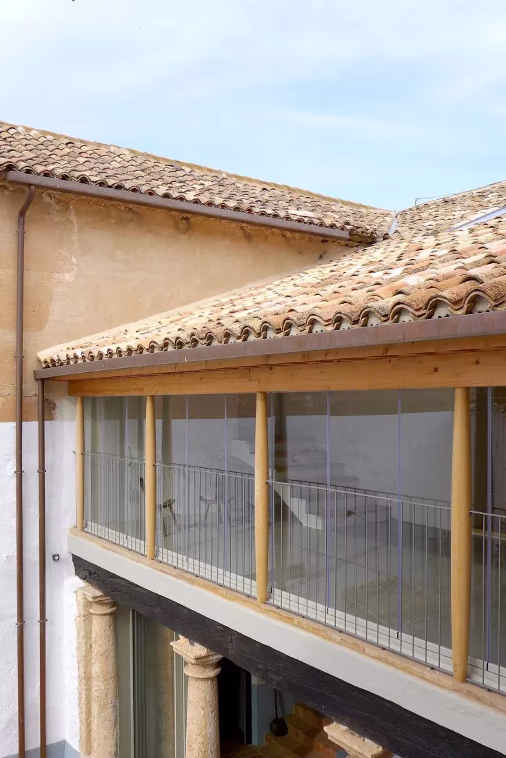 Galería acristalada con carpintería de madera junto a las cubiertas de teja del patio de la Casa de la Sevillana
