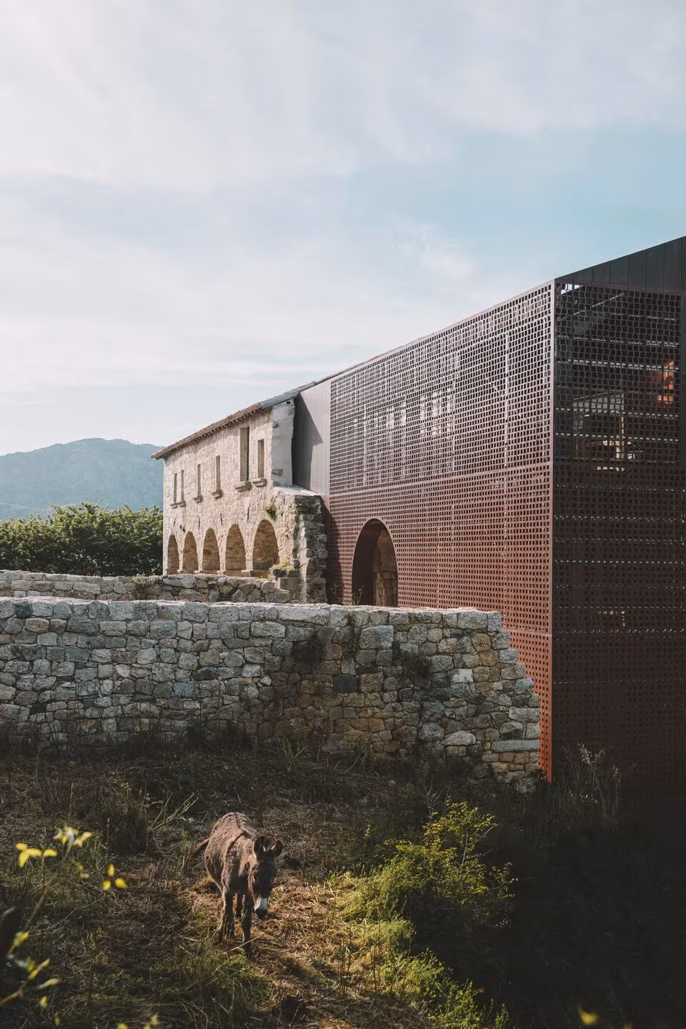 Convento Saint-François con volumen de metal perforado y arcadas de piedra, con un jabalí en primer plano