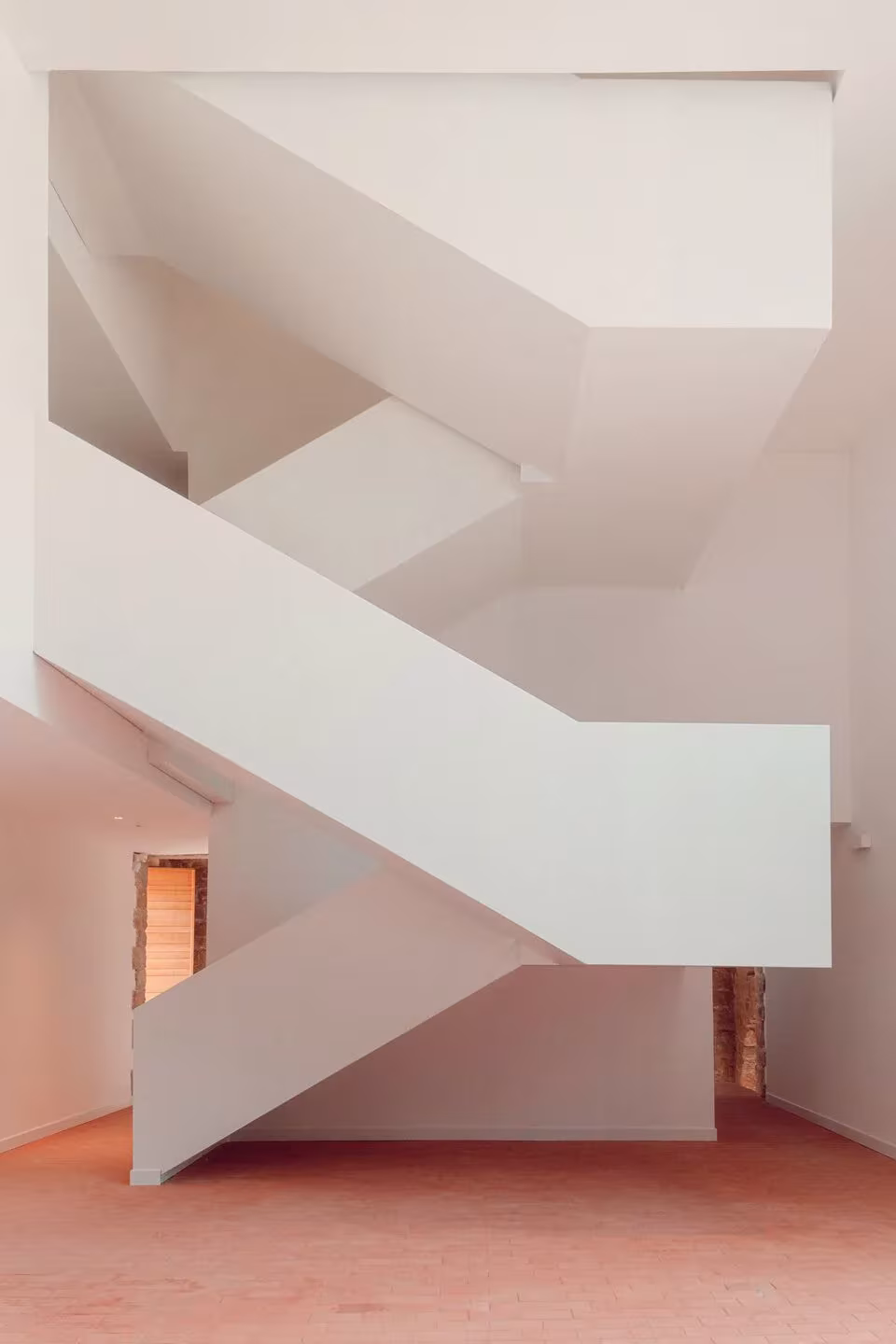 Escalera escultórica blanca con tramos en zigzag sobre suelo rosado en el Convento Saint-François