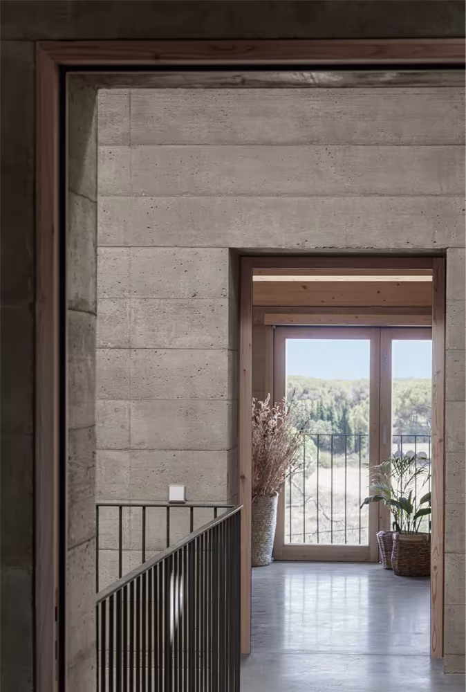 Puerta de madera acristalada abierta al campo vista desde un paso con baranda metálica en la Casa 1627