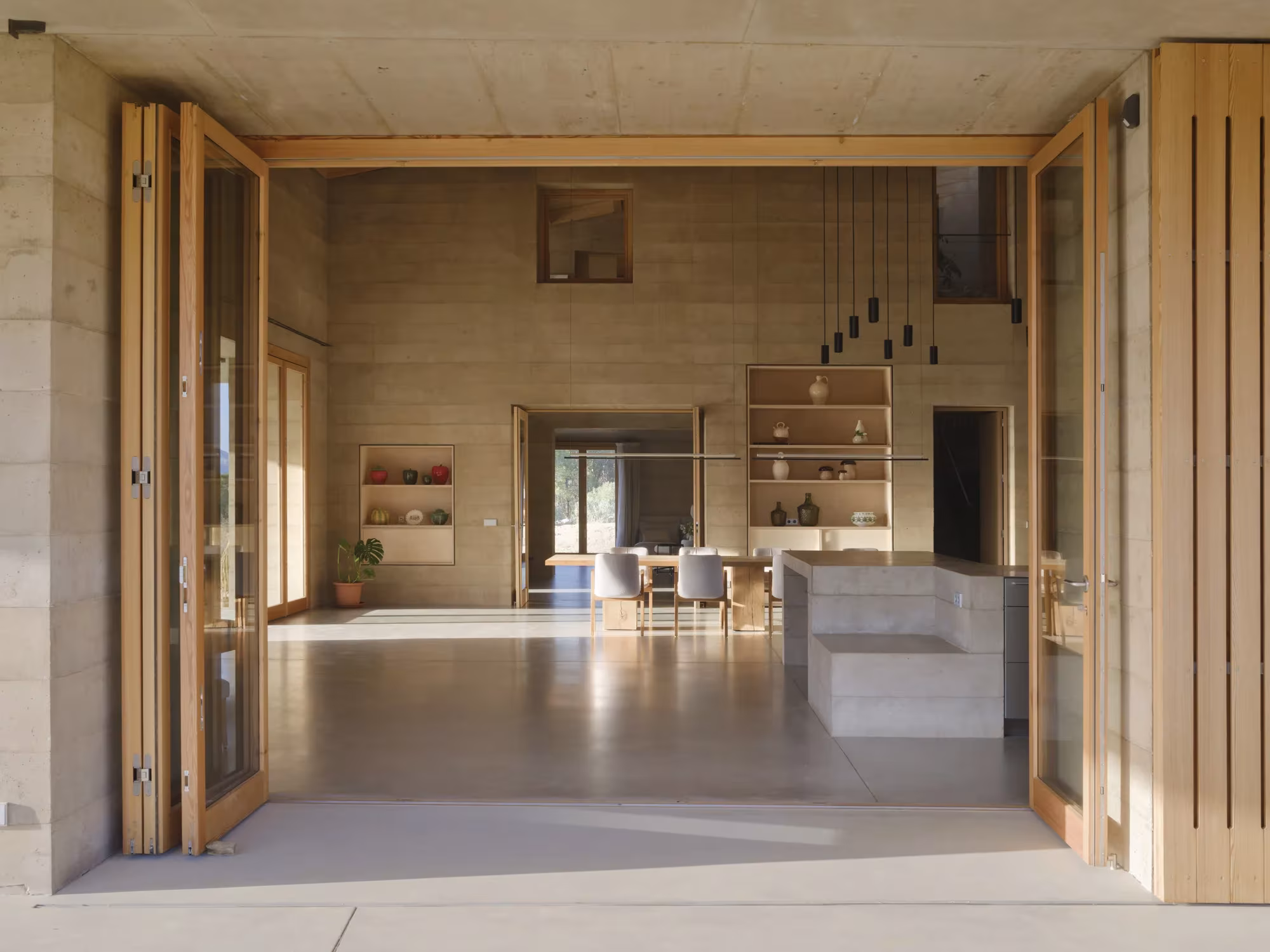 Entrada de la Casa 1627 con puertas plegables de madera abiertas hacia la cocina y el salón