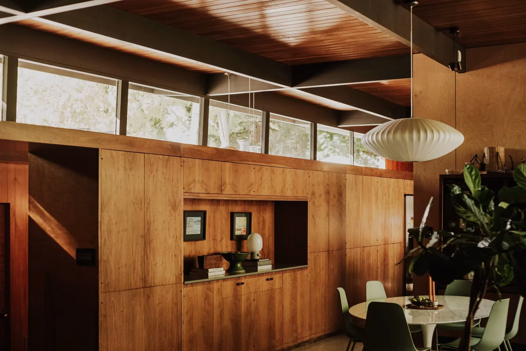 Comedor de la Residencia Nittler con mueble de madera y hueco pasante bajo ventanas altas