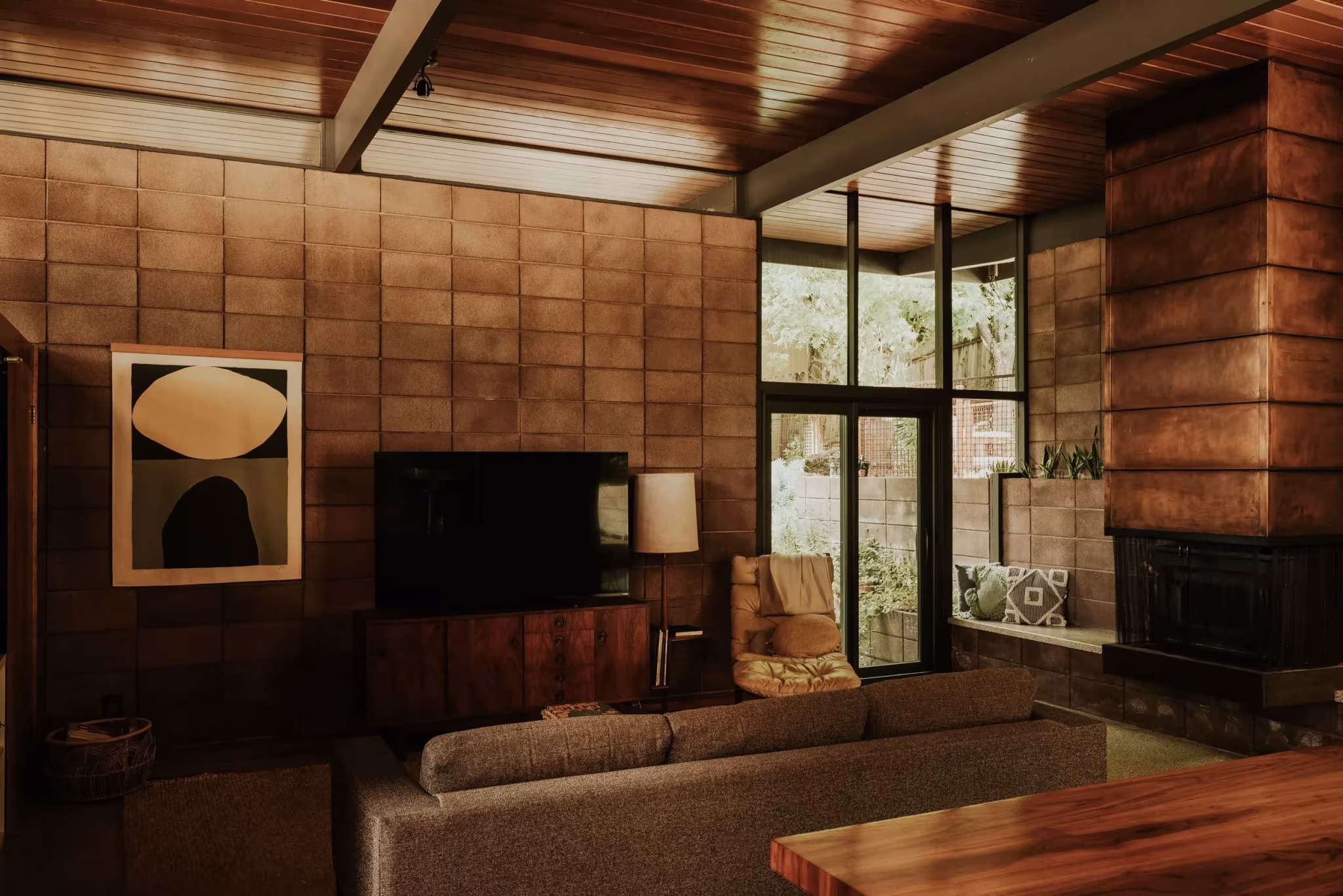 Sala de estar de la Residencia Nittler con techo de madera, vigas de acero y muro de bloque de hormigón