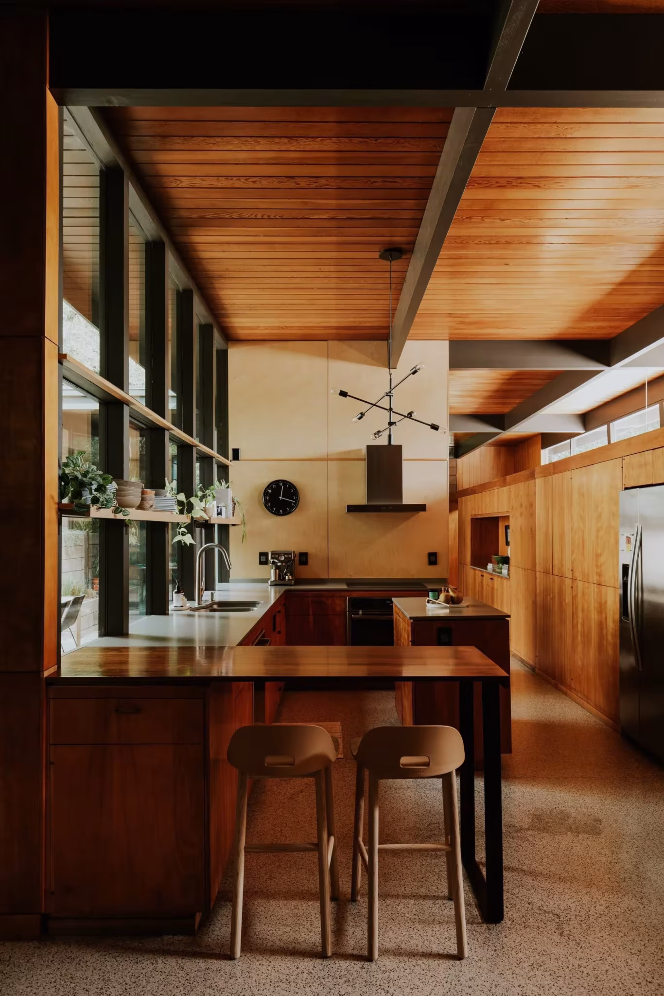 Cocina de la Residencia Nittler con barra y taburetes bajo un techo de madera y ventanas altas