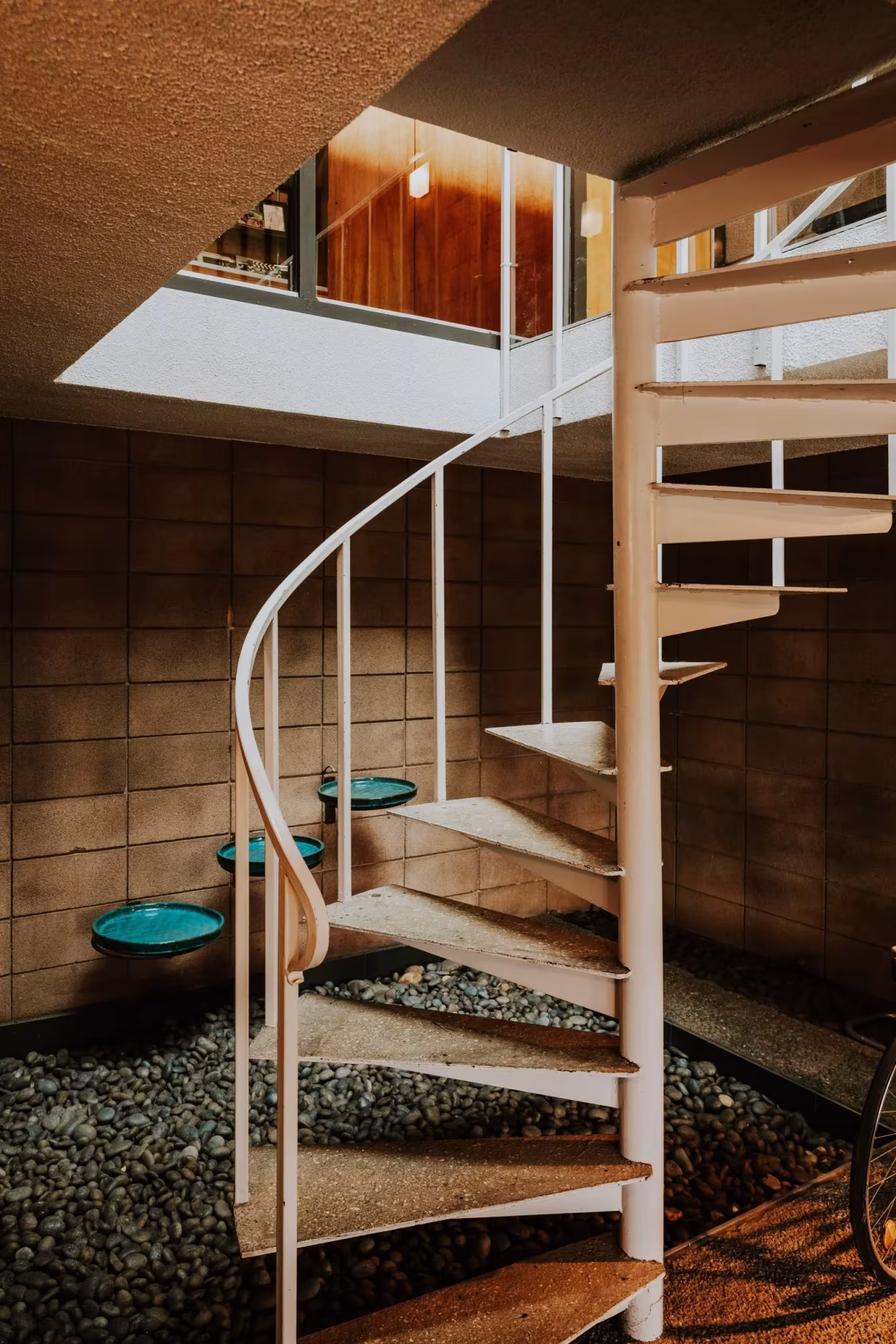 Escalera de caracol blanca bajo un lucernario junto a un lecho de grava en la Residencia Nittler
