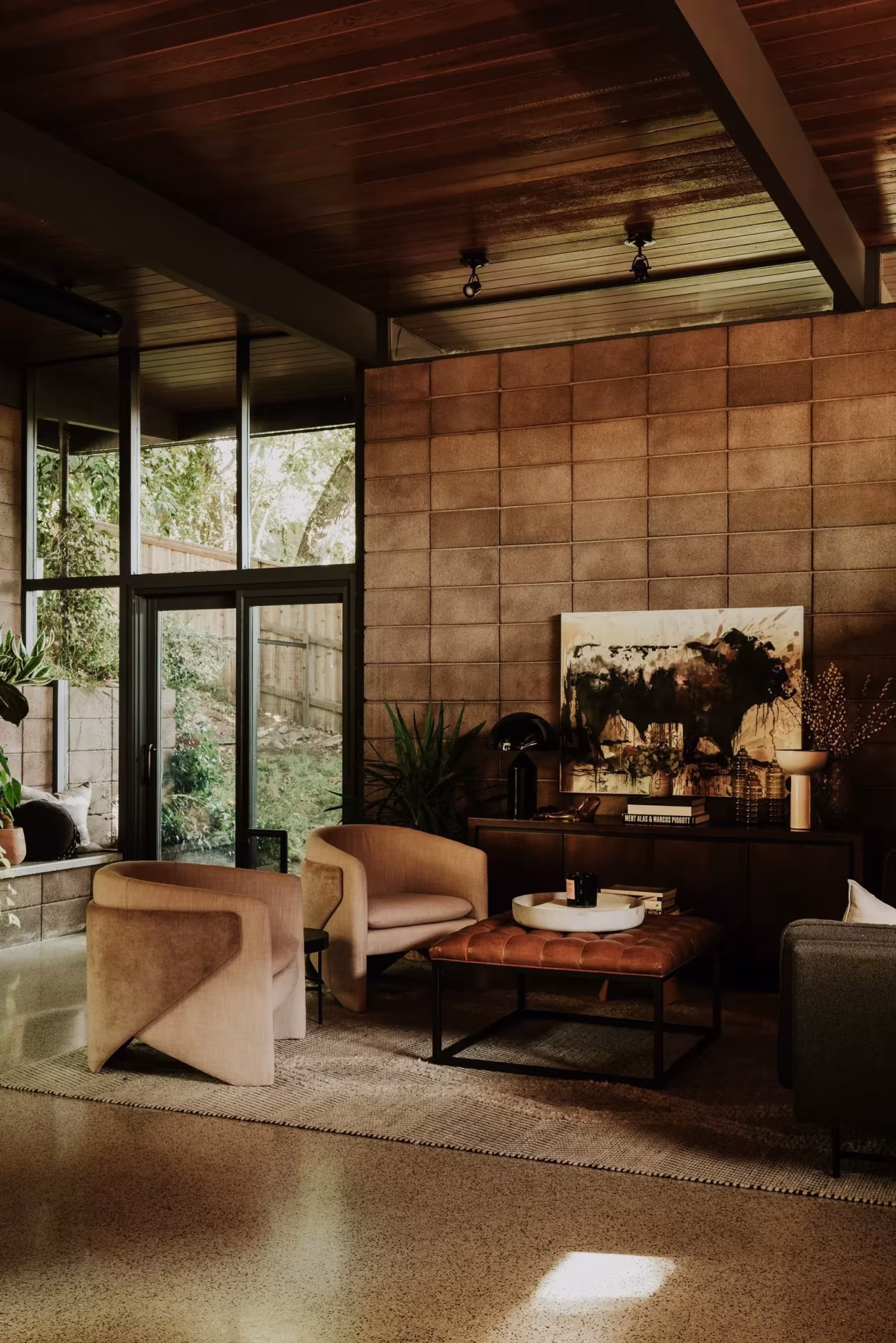 Rincón del salón de la Residencia Nittler con butacas, mesa baja y muro de bloque de hormigón