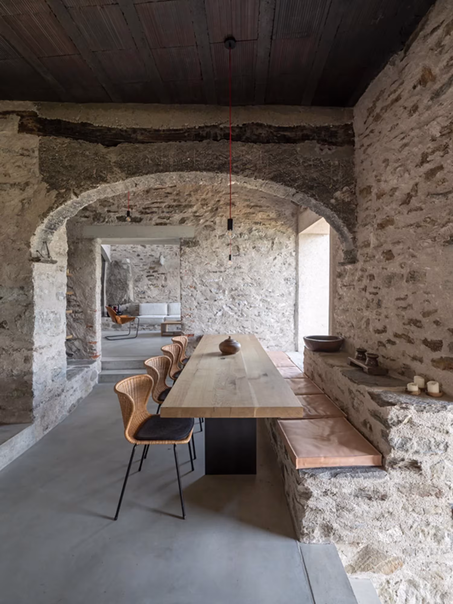 Mesa de comedor de madera bajo un arco de piedra, vista desde la cocina en Transformation House ME
