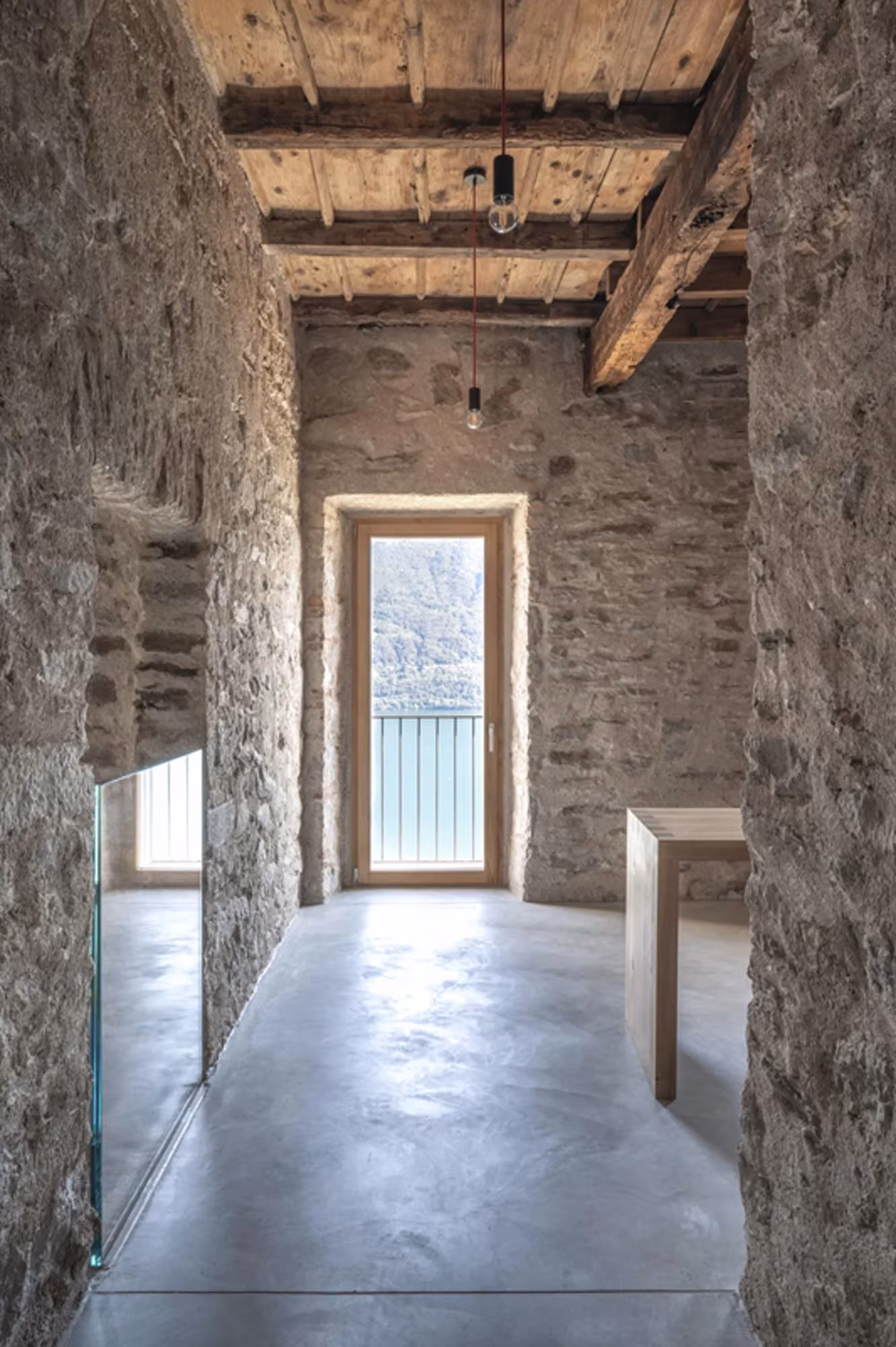 Pasillo de piedra con vigas de madera antiguas y una puerta balconera al fondo en Transformation House ME