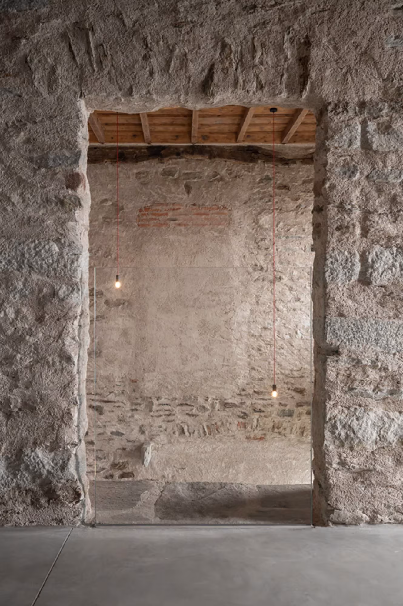 Hueco en un muro de piedra con vigas de madera vistas y restos de revoco en Transformation House ME