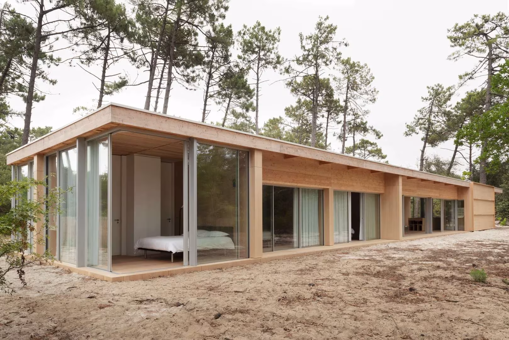 Esquina de la Maison en Bois con paneles de vidrio y dormitorio visible tras la fachada de madera