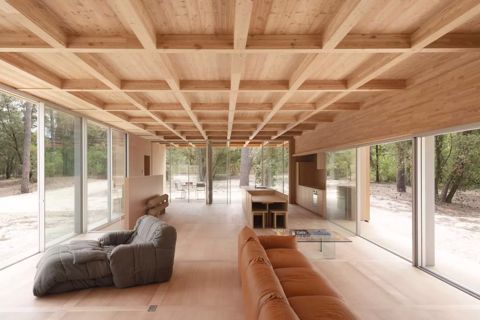 Estancia continua de la Maison en Bois con cristaleras a ambos lados y techo de entramado de madera