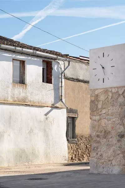 Torre del reloj de piedra y revoco blanco junto a las casas tradicionales de Valverde de Campos