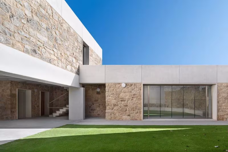 Fachada del patio de la Casa Consistorial de Valverde de Campos con zócalo de piedra y cristalera corredera