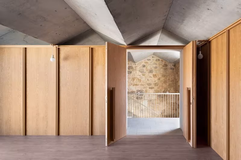 Sala con puertas de madera abiertas hacia el muro de piedra y la barandilla en la Casa Consistorial de Valverde de Campos