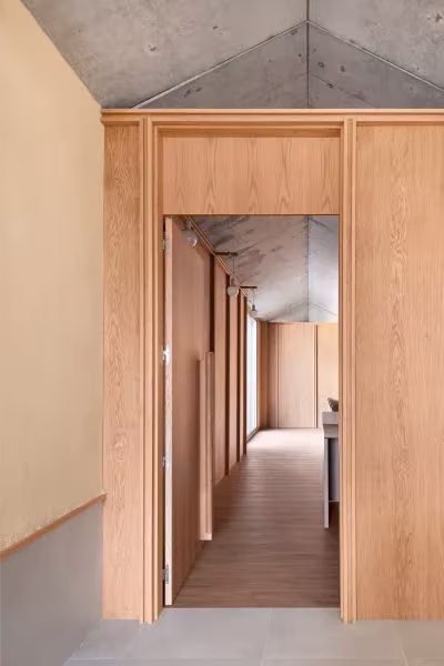 Pasillo revestido de madera con marco de roble bajo un techo de hormigón en la Casa Consistorial de Valverde de Campos