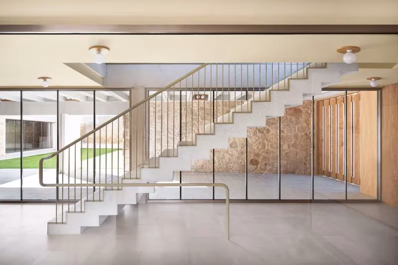 Escalera blanca de hormigón con barandilla de latón junto a un patio en la Casa Consistorial de Valverde de Campos