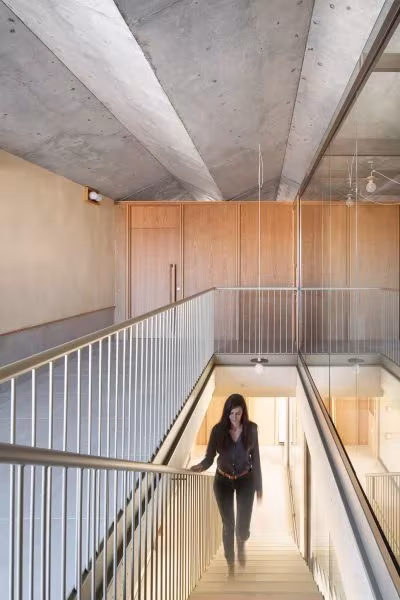 Escalera con barandilla metálica hacia una sala revestida de madera en la Casa Consistorial de Valverde de Campos
