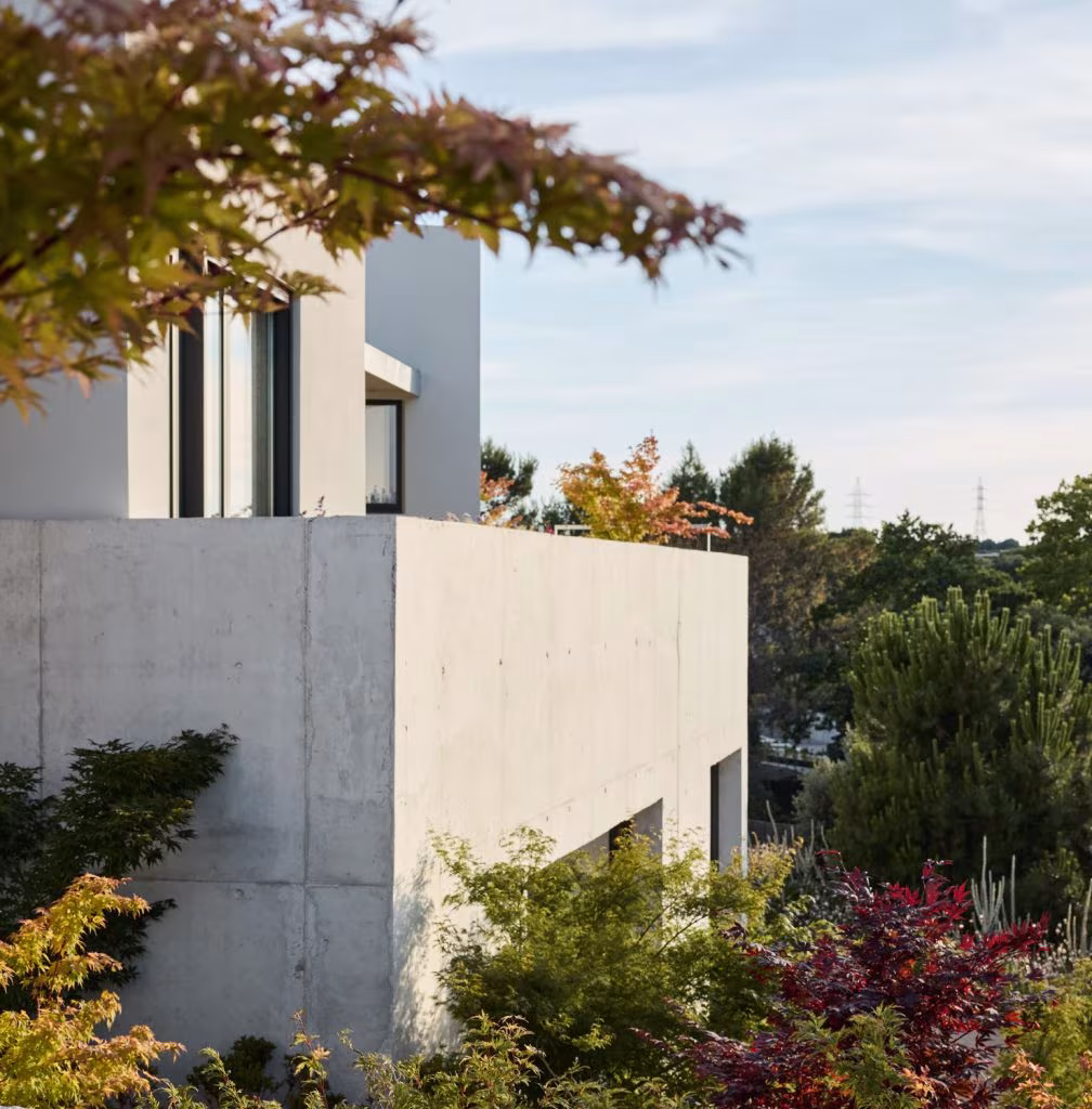Concrete structure with a terrace at ÁBATON’s Casa Brisa, nestled among autumnal shrubs and trees
