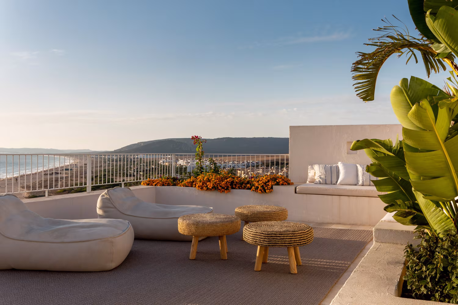 Terraza con vistas al mar y a la costa, pufs y mesas auxiliares de fibras naturales