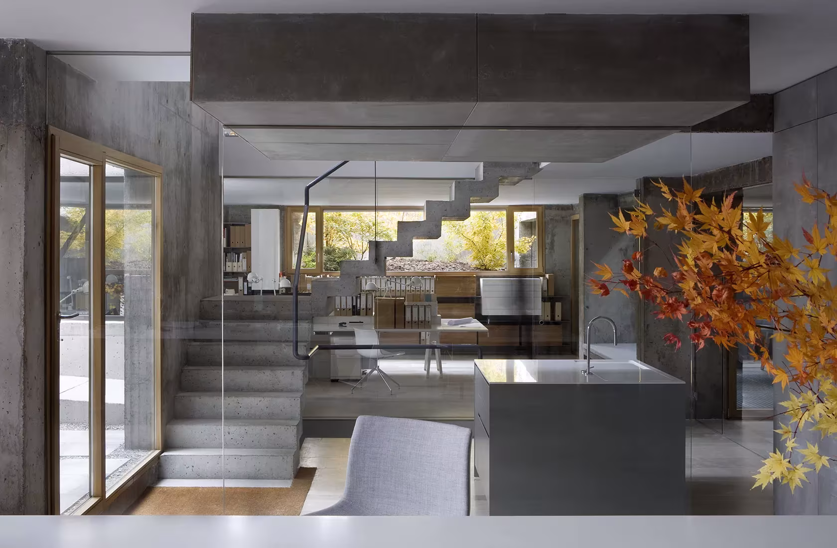 Interior with gray walls and wood, featuring a kitchen island, a staircase, and a glass door leading to a patio