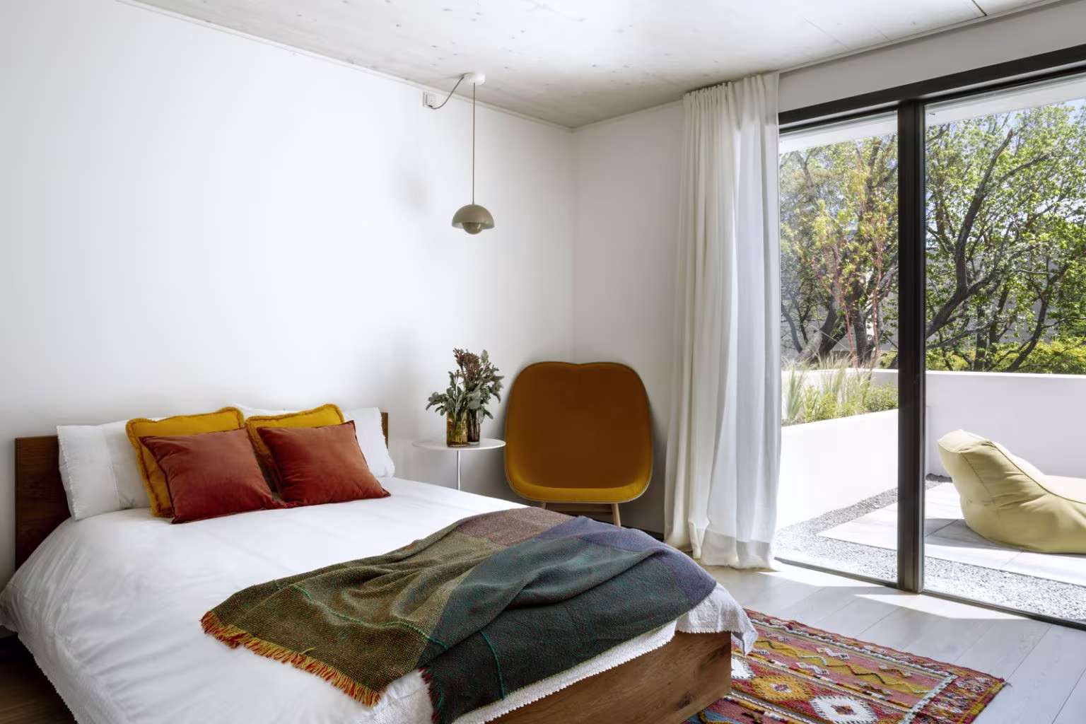 Dormitorio con ropa de cama blanca, mantas verdes y corredera acristalada a la terraza en el Proyecto AF