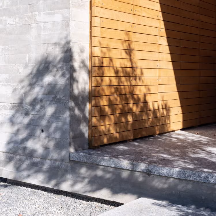 ABATON-Panteon-19 Meeting of exposed concrete and horizontal timber slats with branch shadows at El Panteón