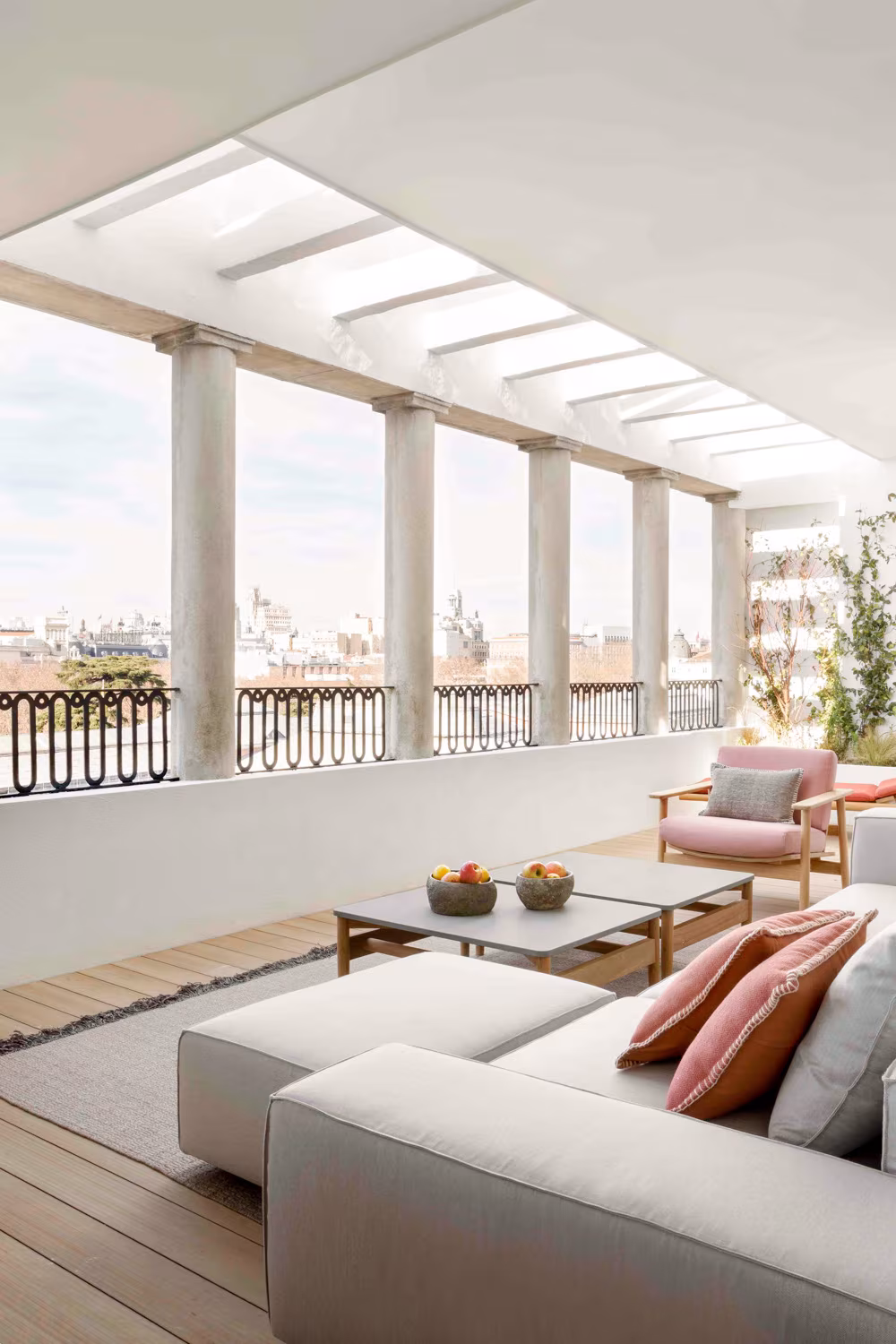 Penthouse living room with a pillared gallery, corner sofa and city views, the Ático sobre el Parque del Retiro