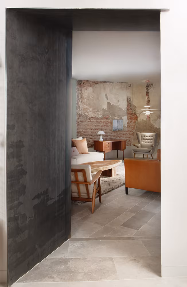 A dark steel pivot door that opens onto a living room with an exposed brick wall at the Batavia store