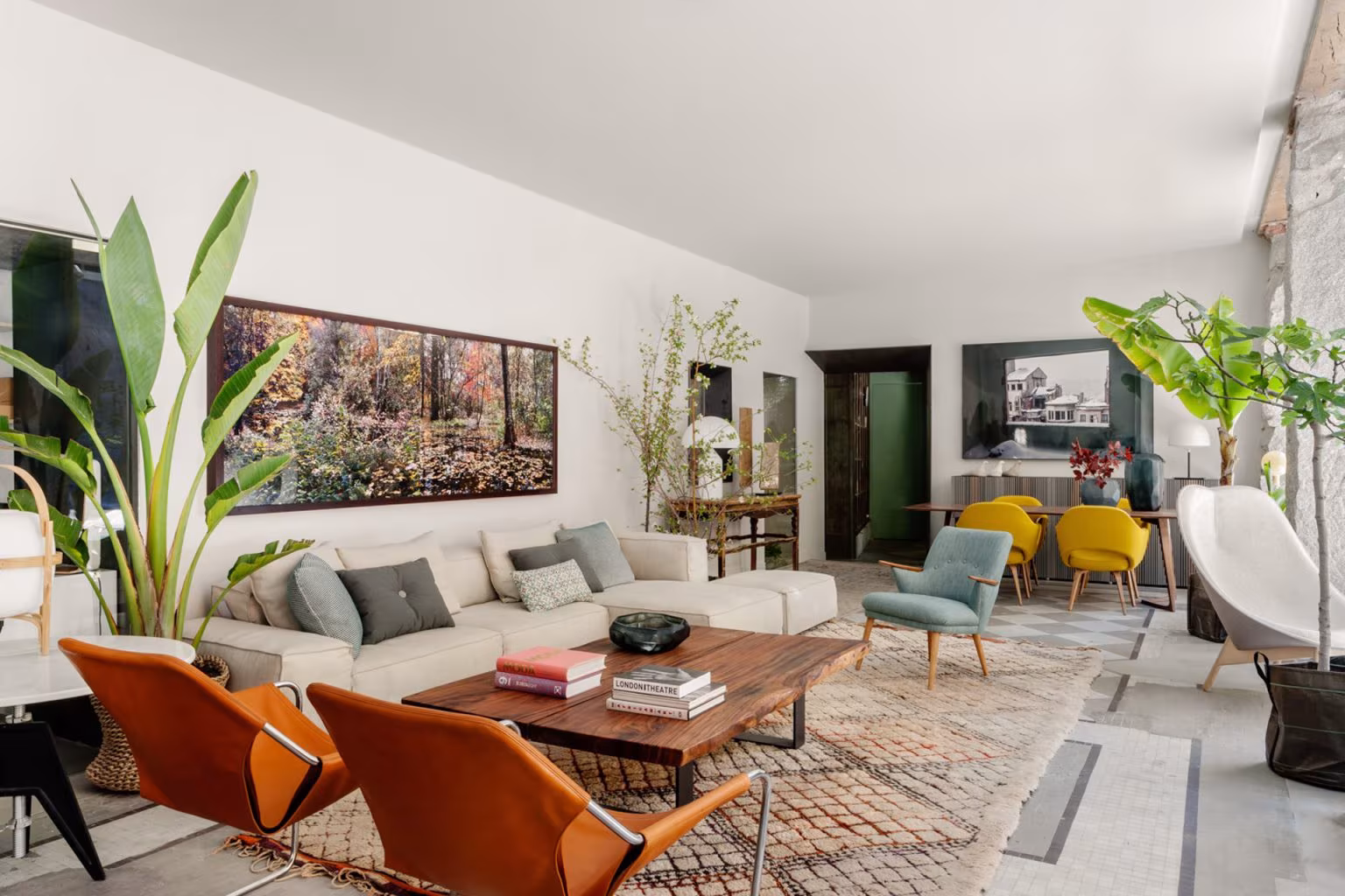 A long room with sofas, orange leather armchairs, rugs, and plants at the Batavia store in Ábaton