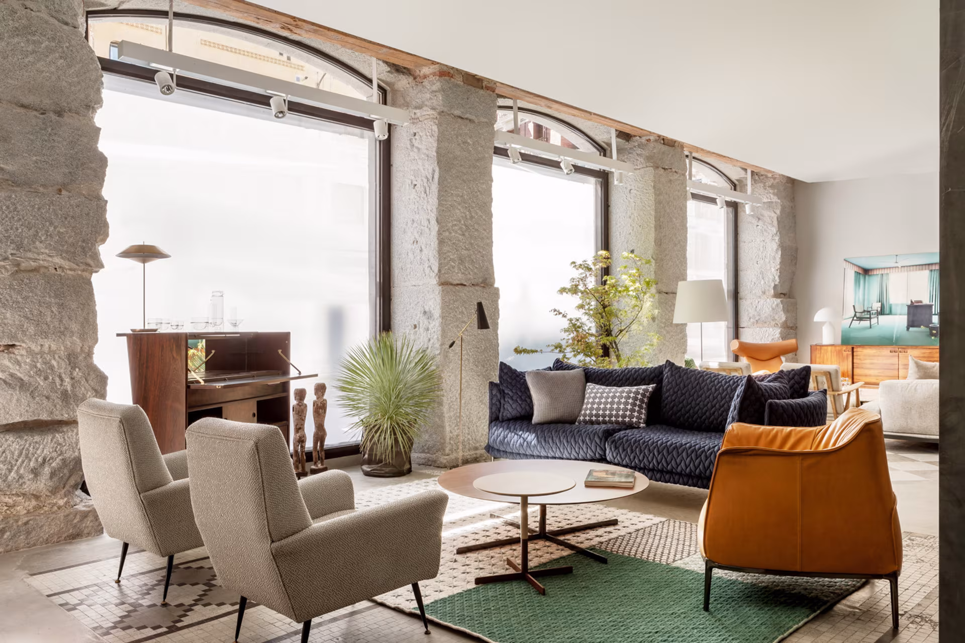 A room with large arched windows, stone walls, and period armchairs at the Batavia store