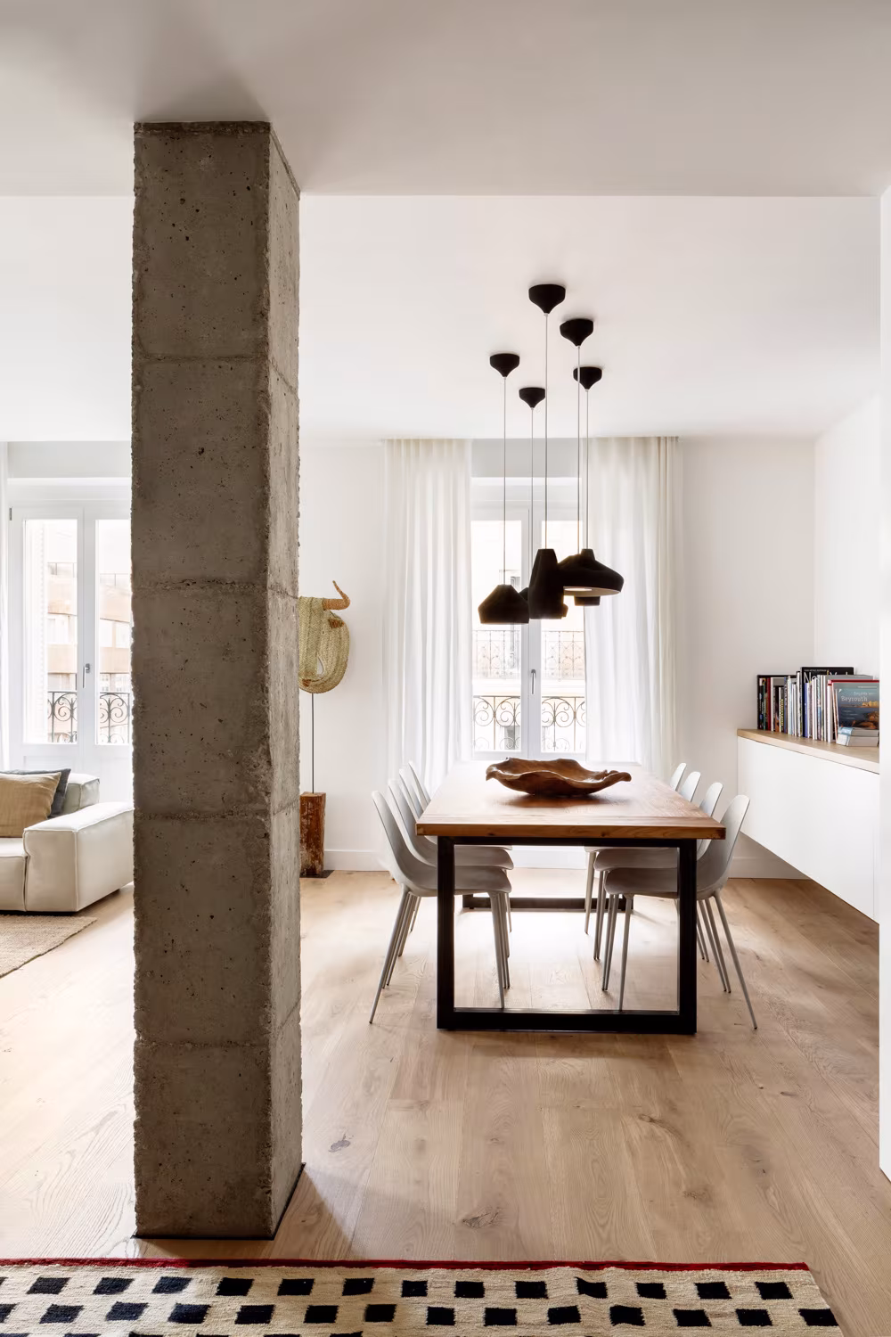 Dining room with an exposed concrete pillar, wooden table and pendant lamps at Casa Ayala