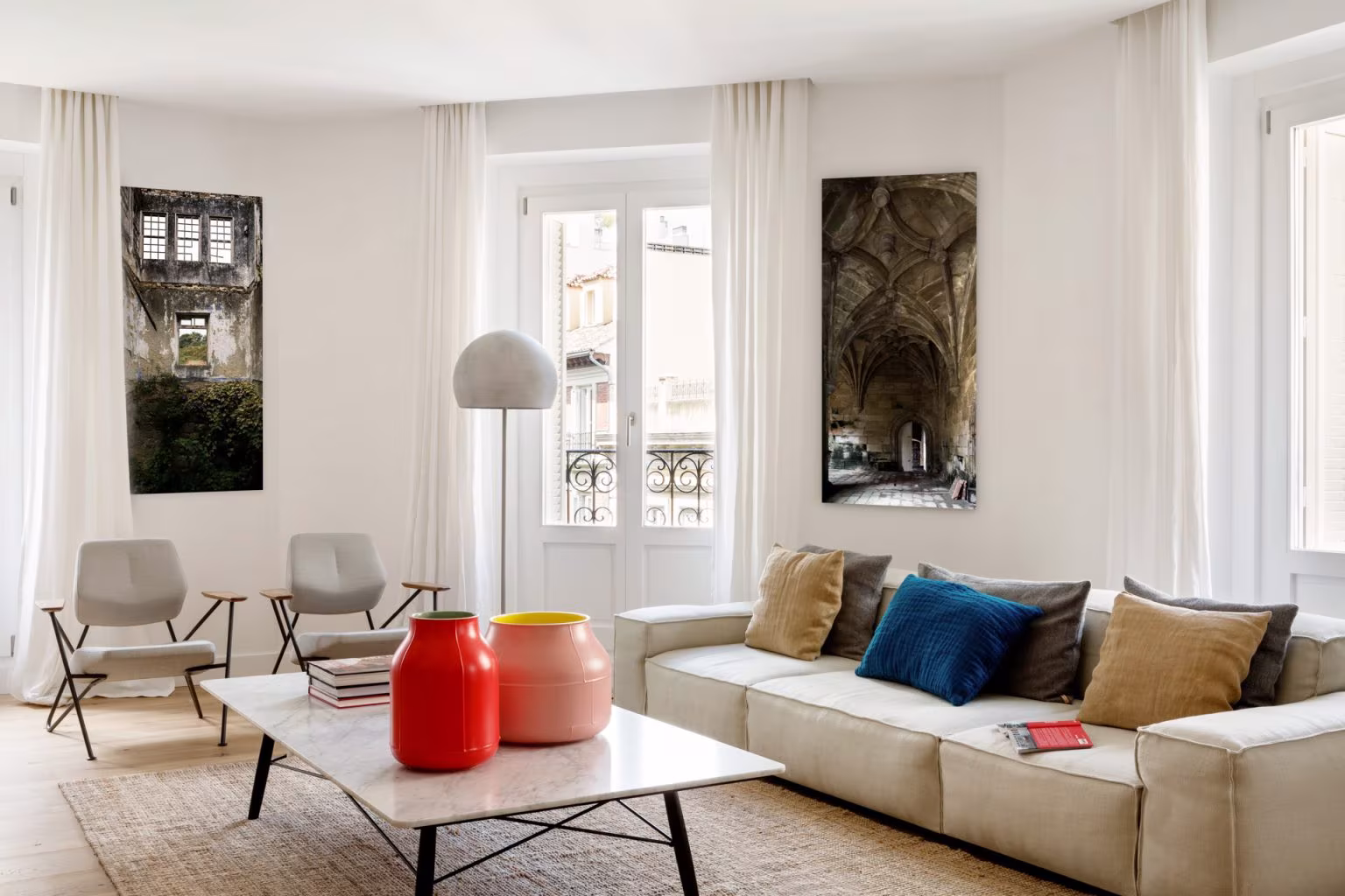 Salón de Casa Ayala II con sofá claro, cojines de colores y cortinas de lino ante ventanas de balcón