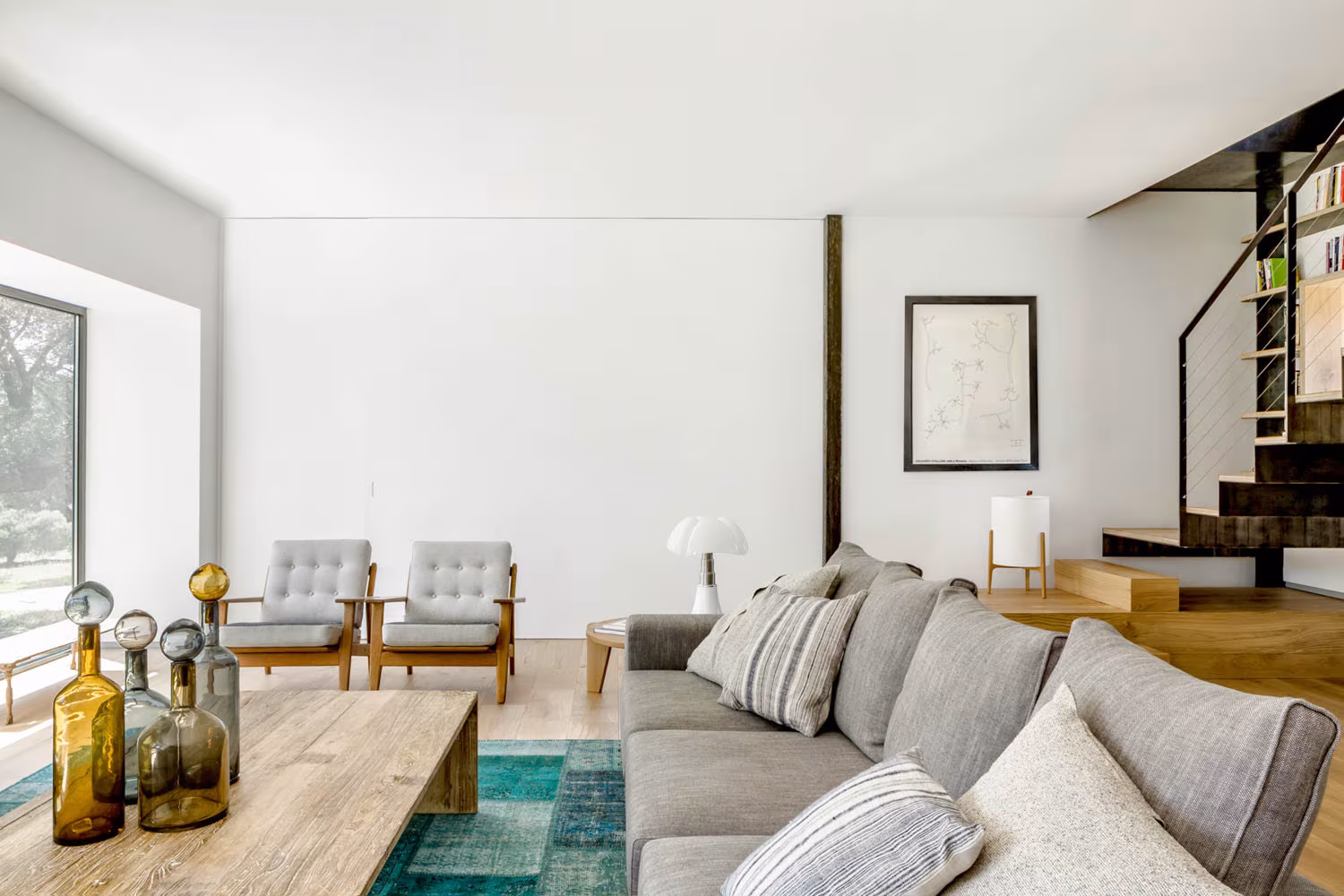 Sala de estar de Casa de Campo LS con la escalera de chapa al fondo y alfombra turquesa bajo la mesa baja