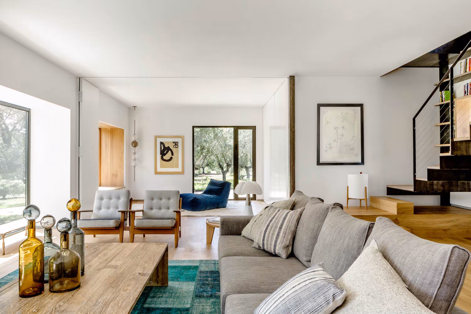 Sala de estar de Casa de Campo LS con sofá gris, mesa de roble, butacas y ventana al encinar