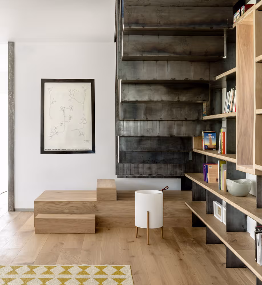 Escalera de chapa oscura con peldaños de madera y estantes de roble en el vestíbulo de Casa de Campo LS