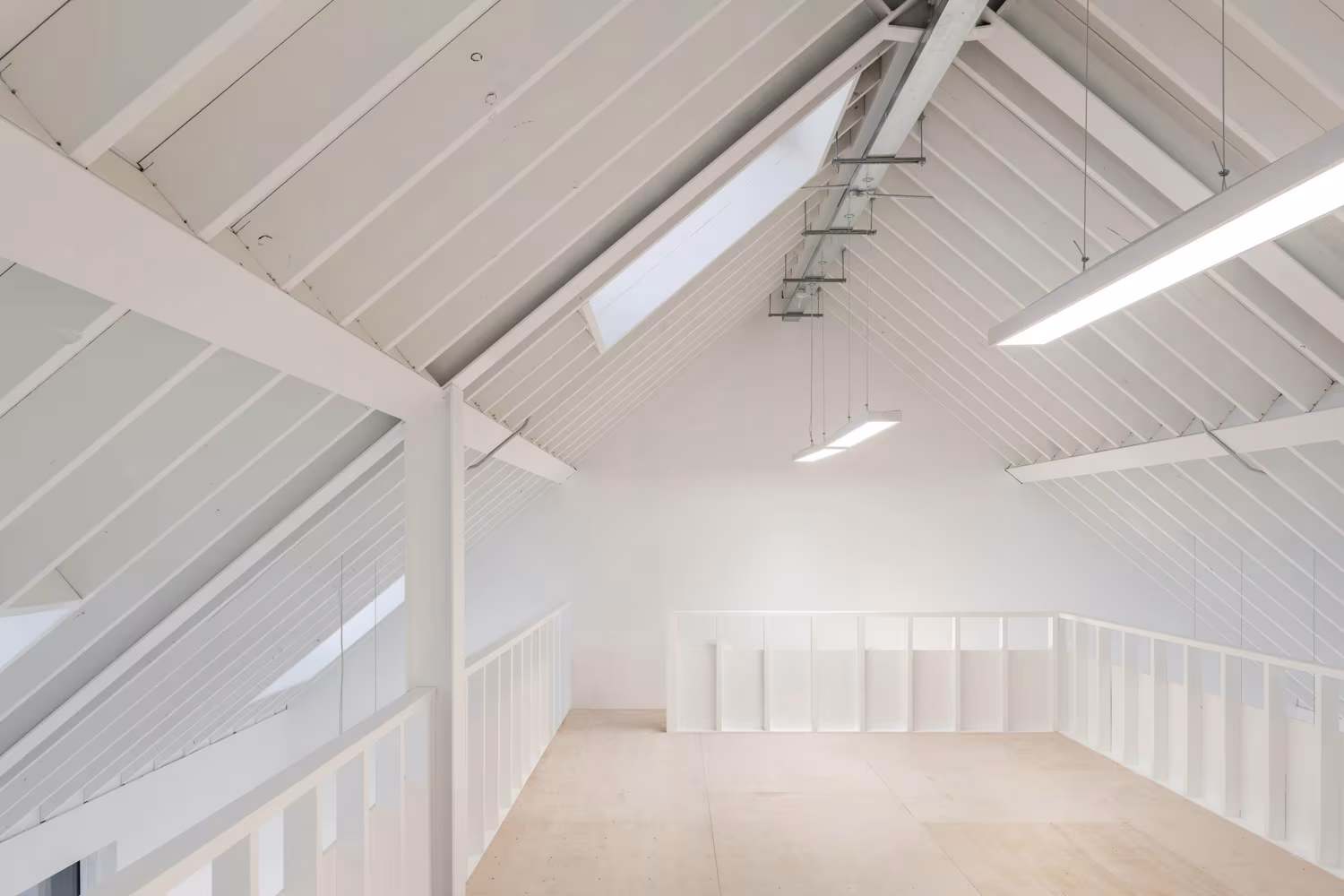 Sala bajo cubierta de Bradbury Works con cerchas pintadas de blanco y un lucernario inclinado