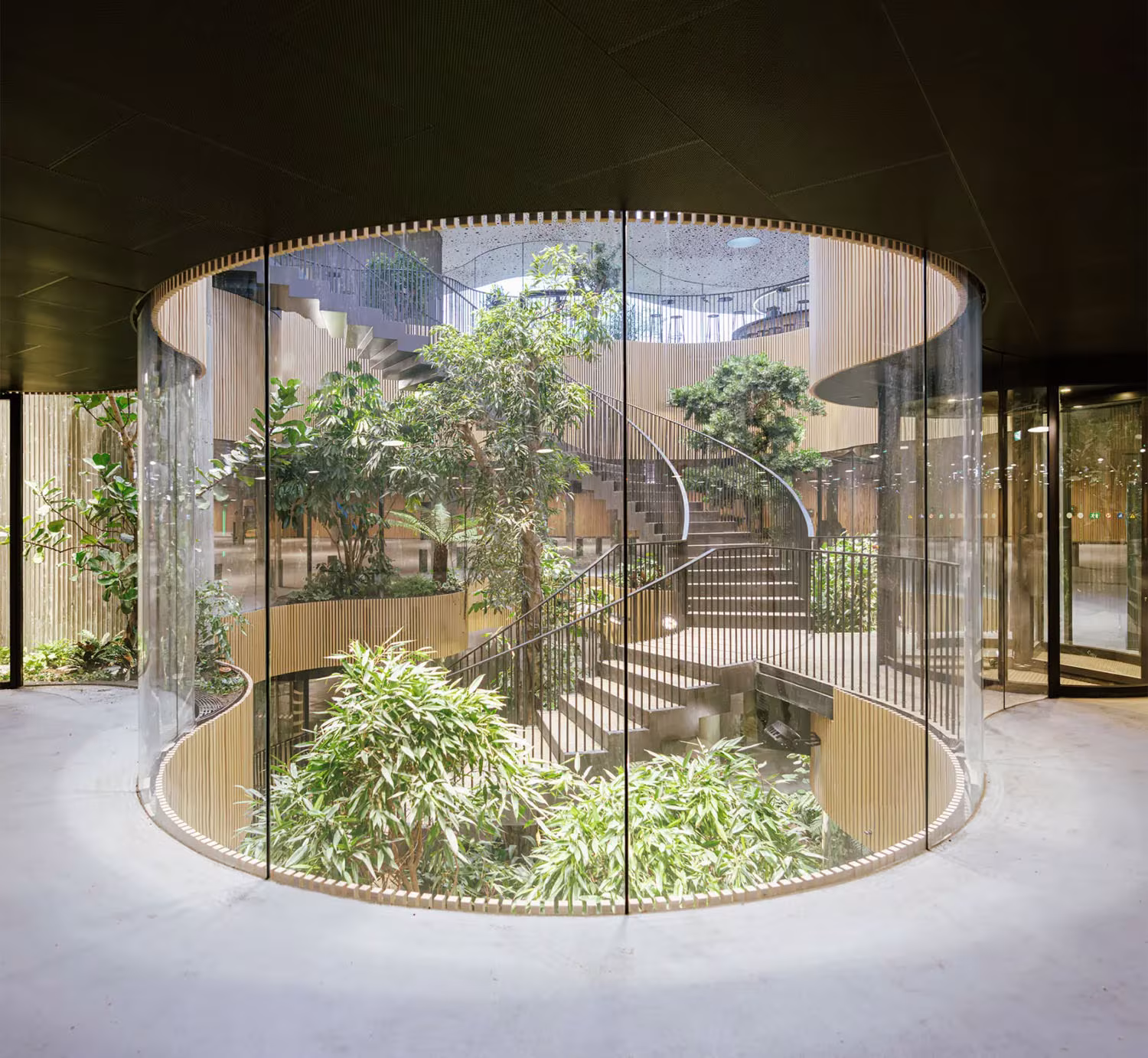 Cilindro de vidrio con escalera helicoidal y plantas en el interior del pabellón del Opera Park