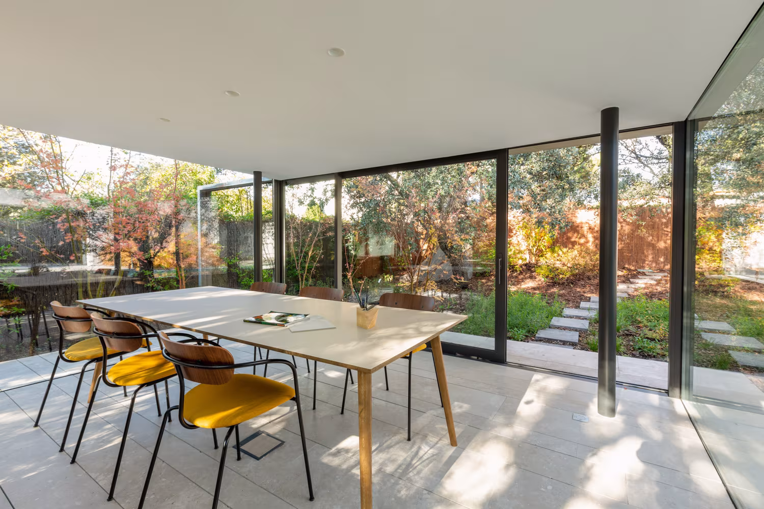 ABATON-pabellon-del-jardin-02 Dining space under the pergola with oak table and yellow chairs open to the garden, Pabellón del Jardín