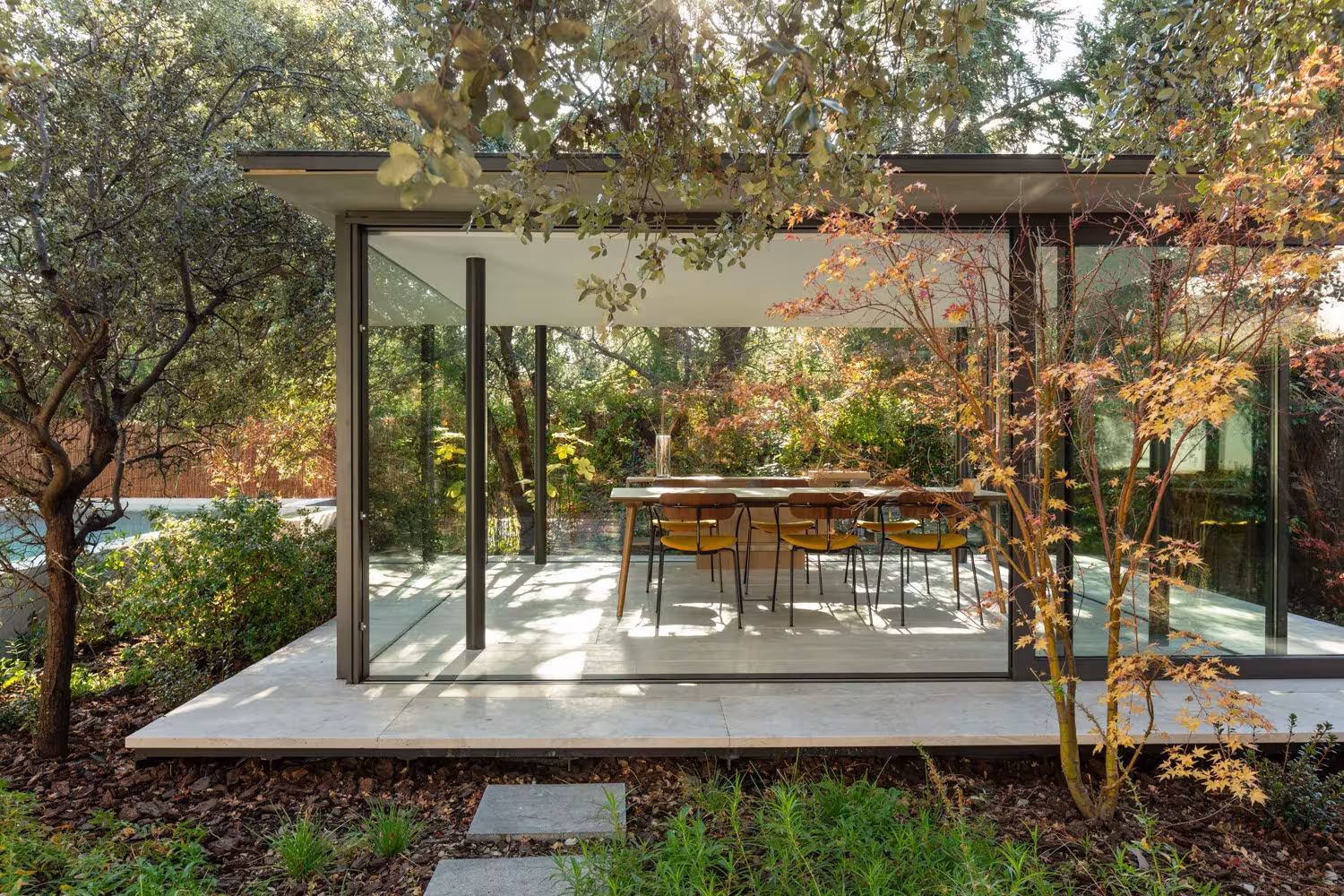 ABATON-pabellon-del-jardin-07 Glazed pavilion with a cantilevered flat roof and dining table surrounded by maples, Ábaton garden