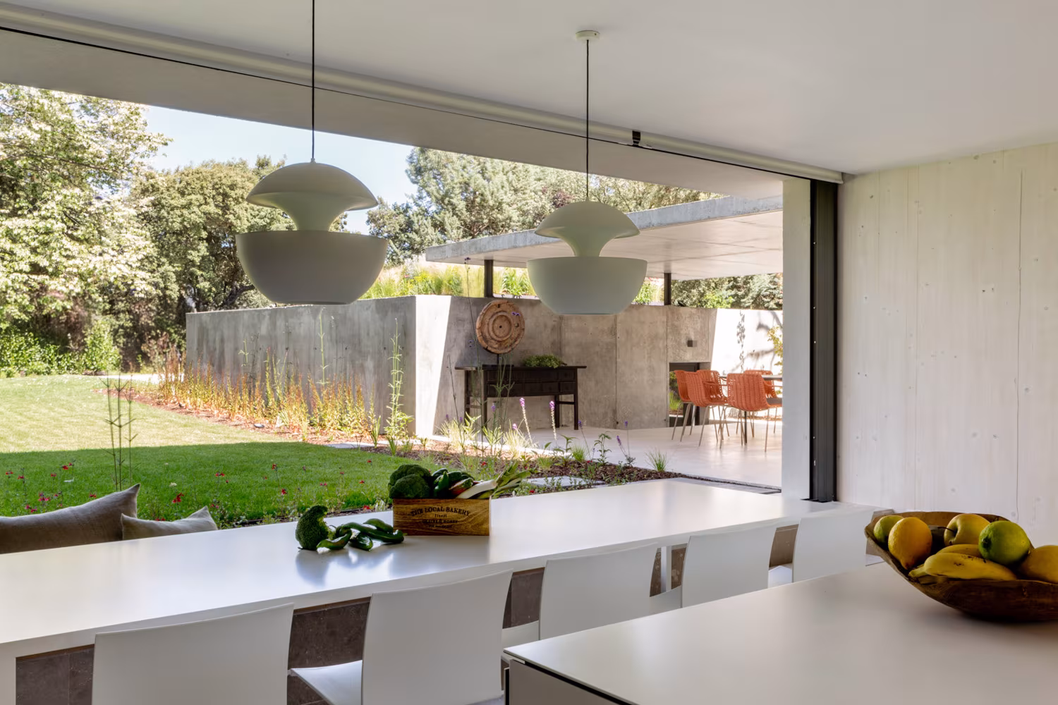 Cocina abierta al jardín mediante una cristalera corredera, con frutas sobre la encimera, en la casa de las luces