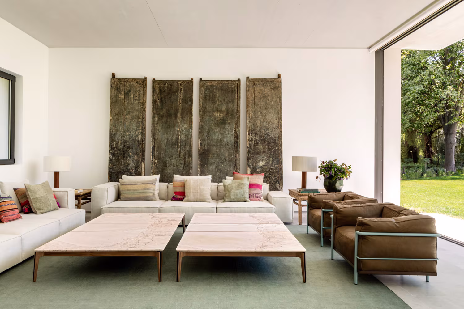 Sitting room with two wooden tables, white sofa and a large botanical panel in Casa de las luces