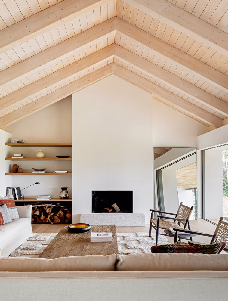 Living room under a timber gabled roof with white fireplace and shelving at the Cabaña en La Vera