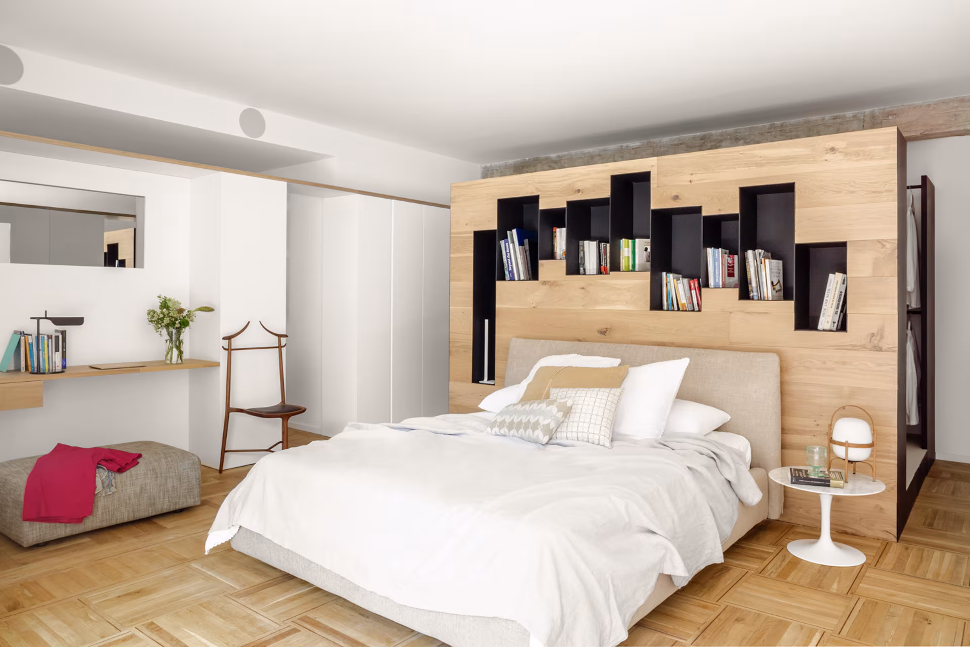 Dormitorio con cabecero de roble y estantes negros, parquet en espiga y escritorio en la reforma del Barrio de Salamanca