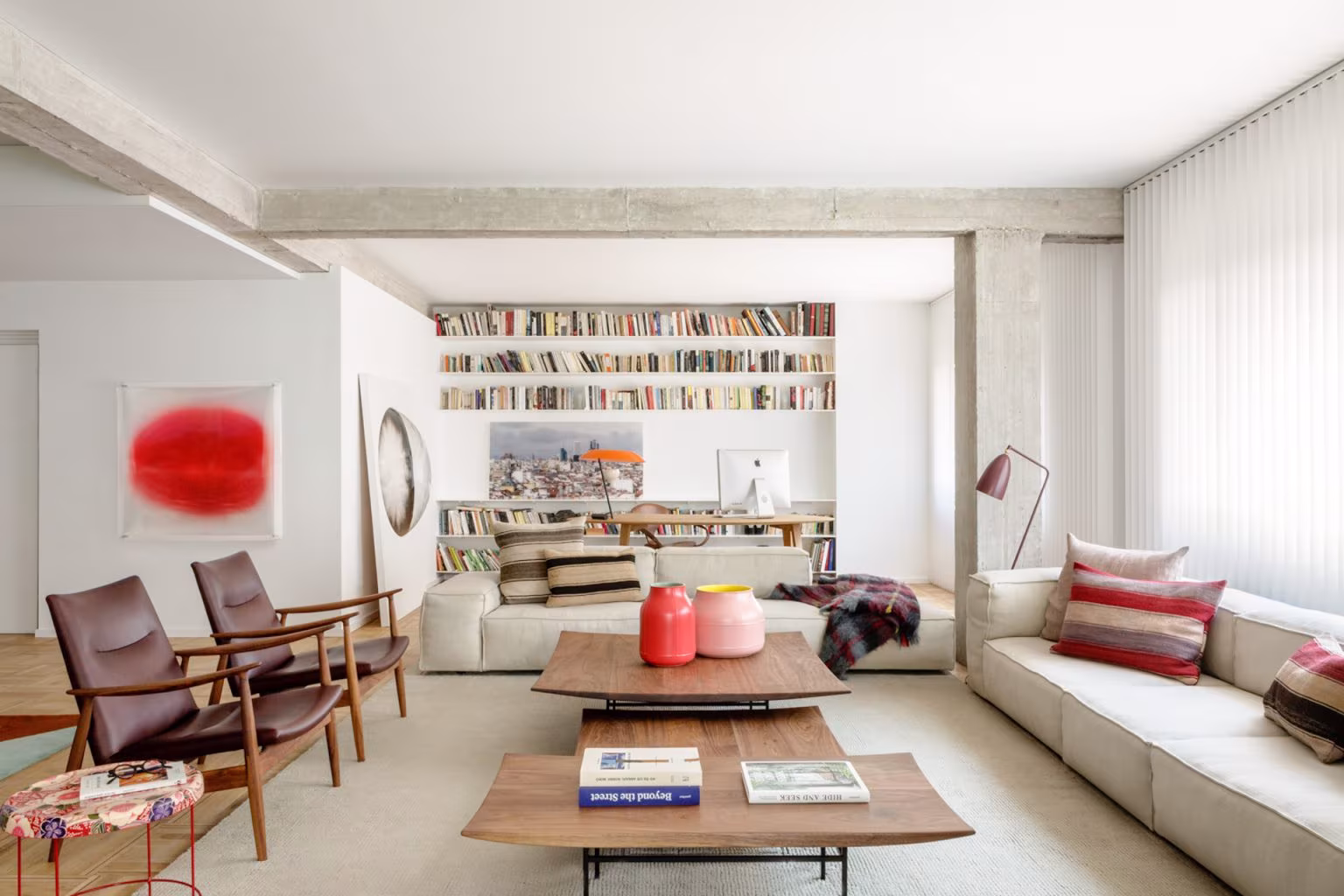 Living room of the Barrio de Salamanca refurbishment with concrete beams, leather armchairs and a long bookcase