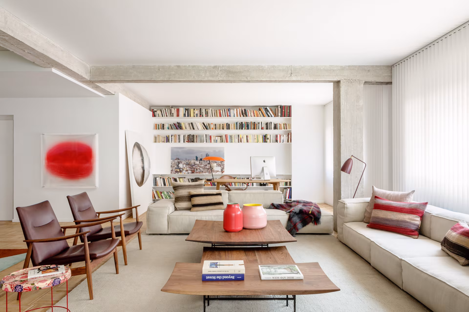Living room of the Barrio de Salamanca refurbishment with concrete beams, leather armchairs and a long bookcase
