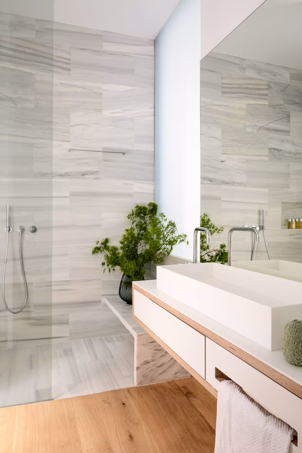 Baño de la reforma integral en Almagro con ducha, mármol veteado, lavabo de cubeta y mueble de madera clara